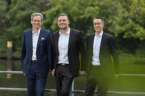 Drei Männer im Anzug im Grünen