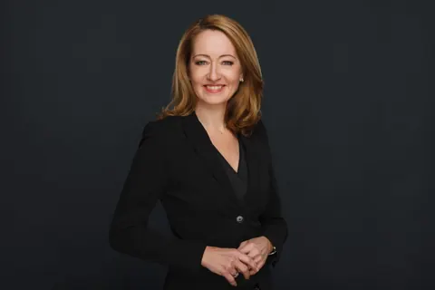 Frau im schwarzen Blazer vor dunklem Hintergrund