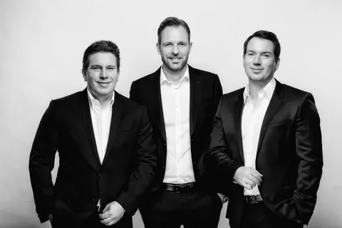 Schwarzweiß-Portrait von drei Männern im Anzug