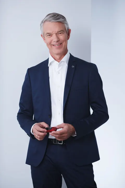 Mann im dunklen Anzug, Ganzkörperportrait vor hellem Hintergrund