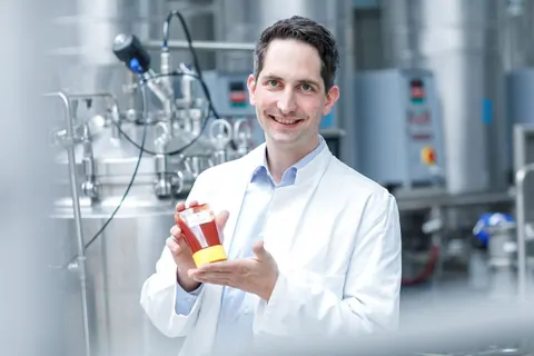 Mann im Laborkittel hält ein Produkt in die Kamera