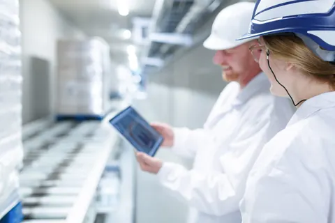 Mitarbeiter in Schutzkleidung mit Tablet in der Produktion