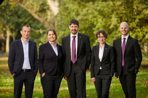 Fünf Personen in Businesskleidung im Park