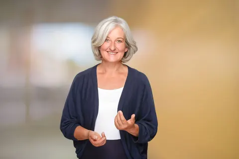 Frau mit grauem Haar vor warmem Hintergrund